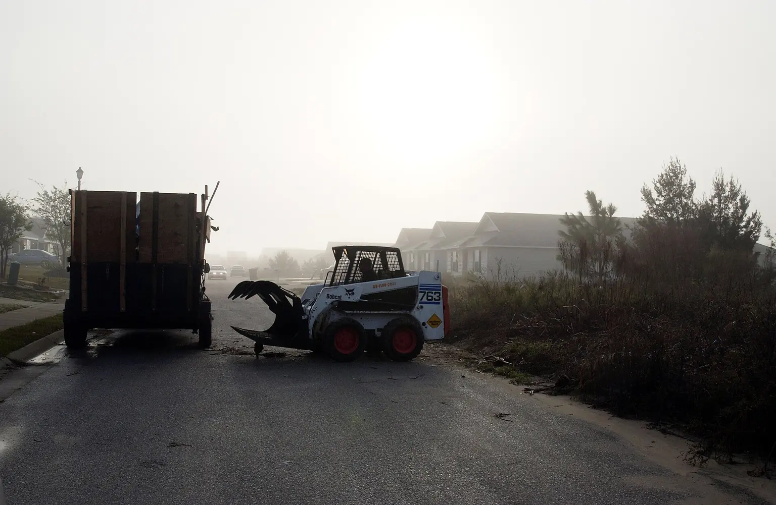 Loader and debris truck working a roadside in the Pensacola area — What Factors Affect Grapple Truck Pickup Pricing in Daytona Beach?